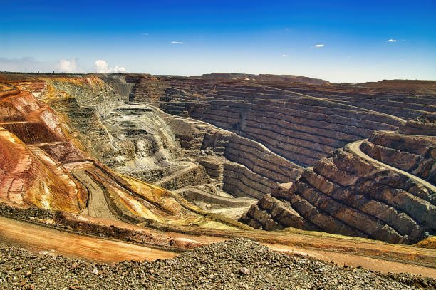Open-pit surface mining operation with heavy machinery at golden hour.