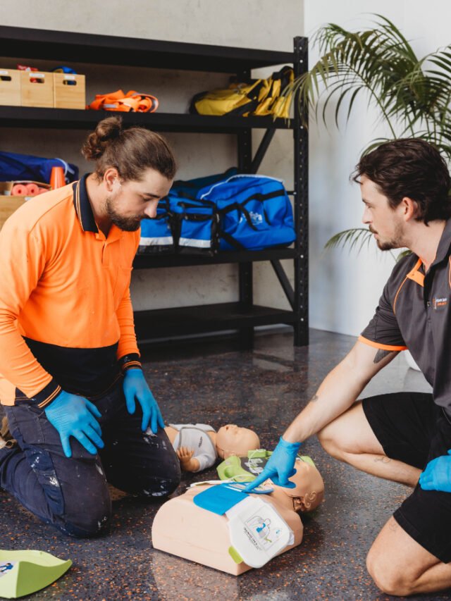 First aid training in a bright classroom with an instructor demonstrating on a manikin.